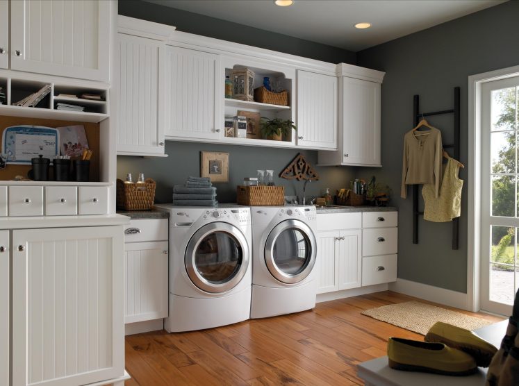 a remodeled laundry room with built in cabinets and drawers for organization