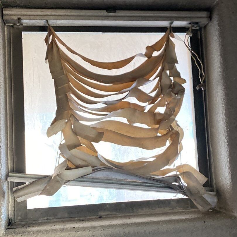 a window with blinds melted by a house fire